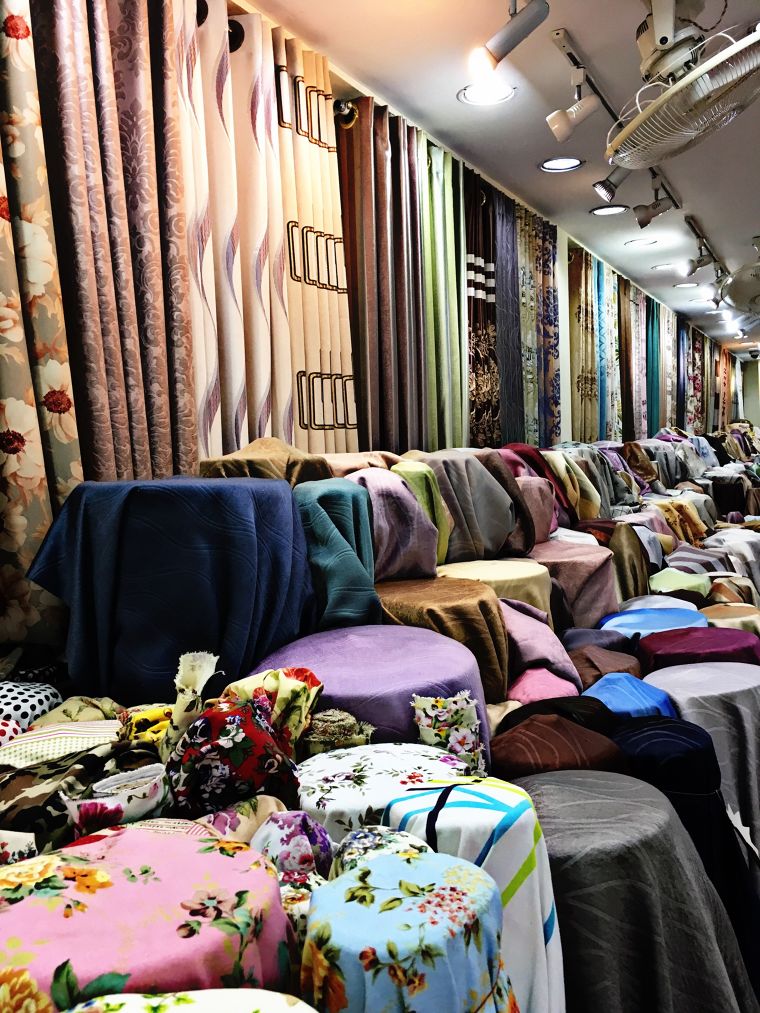 Pahurat Fabric Market (Little India)&nbsp;Curtains Store located&nbsp;right on Pahurat Road across from China World. It is a short walking distance from The Old Siam Plaza as well as India Emporium.Modern trends are moving towards do-it-yourself models of living. Do-it-yourself bags, furniture, clothes, and even curtains have become the norm. Instead of buying the curtains ready made or having them stitched by professional tailors, many people choose to buy curtain fabrics and make the curtains themselves. There are many good reasons for why do-it-yourself options are great especially in the case of curtains. Curtain fabric shops have a great variety of fabrics to choose from, and the best thing is all of these fabrics could be used to make curtains.Curtain fabrics come in all kinds and forms; they vary in features, weight, transparency, textures, and designs. The only thing they seem to share in common is that one could stitch curtains out of them and hang them over a window. The most convincing argument to go for do-it-yourself curtains is that you would get so many choices to make when selecting the fabric. Of course, the fact that you would choose to make do-it-yourself curtains in the first place is that you get the option to personalize the style that you wish your curtains to have. You can even choose multiple textures and designs for the same curtains and get really creative.When picking out the fabrics at the curtain store, you have to consider several factors in deciding which ones fit most to your concept.The color and designs are only the beginning, you would have to touch the fabrics and get a feel of the texture. You also have to decide how hard or soft you want your curtains to feel, whether you want the fabrics to be heavy or light, rough or smooth etc. All of these factors affect how they drape over the windows in your home.In general, the curtain fabrics that make the best finished products are the ones with the highest thread counts. The thread count in fabrics determine how durable they are as well as how heavy they are. Heavier curtains tend to drape better than the lighter ones composed of fabrics with lower thread count. Great curtain fabrics are the satin jacquard, linens, cotton, velvet etc. The satin jacquard variety is made from polyester which does not tend to hold on to dust, making them a good option for those would like the house cleaning to be easy. The velvet and cotton varieties tend to hold on to more dust, however they are also great options as well despite being more difficult to clean. The velvet fabric has a soft feel, and they exude an elegant appearance that symbolizes royalty. If you are hoping to give your home a more regal look, you could always go for velvet curtain fabrics. In Thailand, the silk curtain fabrics are popular as they are smooth and they also shine better than several other types curtain fabrics.The curtain fabrics also have different functional features, some has a shiny texture and protects against ultraviolet radiation, while others may also share the UV protection layer but possesses a rugged texture. Even UV blocking curtains come in a variety of fabrics. Some curtain fabrics are shiny on one side while has a solid, non-shiny texture on the other, some fabrics are shiny on both sides, while others are not shiny on either side. Some fabrics have a smooth surface on one side and a rough exterior on the other etc. The thickness and weight of fabrics as well as its color determines how well they block out light. The UV protecting curtains are not necessarily completely light blocking as well, although they are still called “blackout curtains” in Thailand. Some curtain fabric shops refer to UV protecting curtain fabrics as “dim-outs” instead to make a distinct differentiation between the light blocking fabrics and the UV blocking ones.The darker color tones also help the fabrics to block out light better than the lighter color tones, even for the same type of curtain fabric. It is a good choice to go for the lighter colors when you want your homes to appear more spacious and voluminous, while it is better to choose the darker colors if you prefer to block out more sunlight.The styles of curtains that you can make with “do-it-yourself” tailoring is numerous and infinite depending on your creativity. You could make some really exquisite curtain styles with laces, rings, and linings, and you also get to design the curtain headings and sheers. You could cut up different curtain fabrics and sew them together and create your own designs. The sky is the limit.Do-it-yourself curtains are always a fun option for those who would like to get creative when getting curtains for their homes. There are a lot of fabric options to choose from and you also get to customize the curtains to whatever you style wish. At ATM Decor, we offer almost a hundred thousand meters of curtain fabrics with different textures, colors, and designs. All of them are available to buy at the meter at competitive prices. We are located right next to Phahurat road. Please contact us about our curtain fabrics at 02 223 4828.We wholesale and retail a variety of curtain fabrics and offer tailoring and installation services as well.